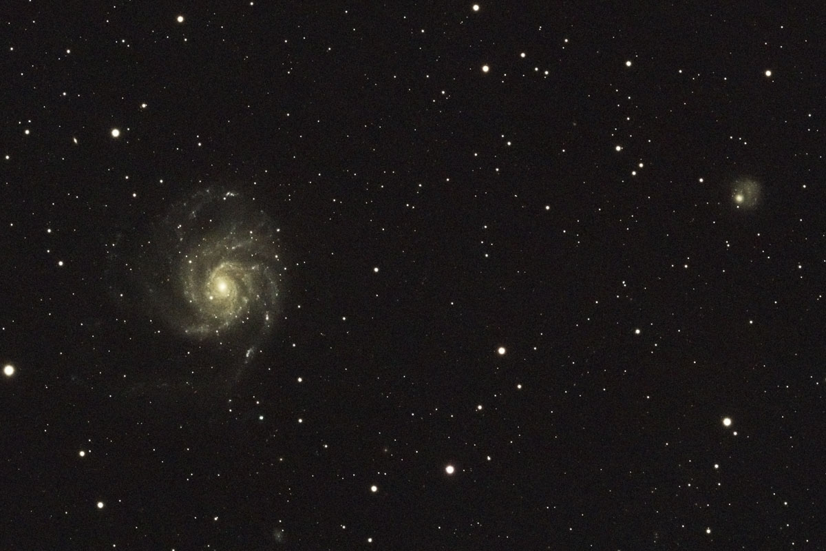 the complex spiral of M101 looks relatively small in the centre-left of this image, with the small blob of NGC 5474 to the upper-right